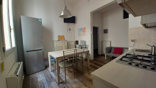 A compact kitchen with a dining area, a refrigerator, a stove, and a window providing natural light. - Cavour 46 Second in Firenze (Florence)
