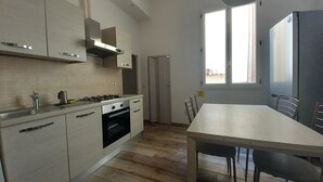 A modern kitchen with a dining area, featuring a stove, oven, and a large window providing natural light. - Cavour 46 Second in Firenze (Florence)