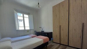 A bedroom with two beds, a desk, a wardrobe, and a window. - Cavour 46 Second in Firenze (Florence)