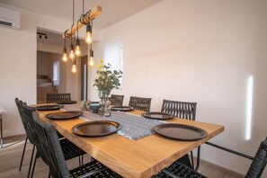 A dining area with a wooden table, black chairs, and a hanging light fixture. - Diminici Villas (Rasa)