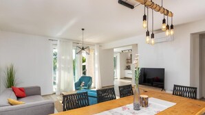 Uma sala de estar moderna com uma mesa de jantar de madeira, um sofá e uma TV.