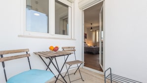 A balcony with a table, two wooden chairs, and a bowl of fruit. - Apartments Tara & Noemi (Rovinj)