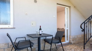 An outdoor patio with a table and chairs, a bottle of wine, and a view of the interior through an open door. - Stancija Lindi (Porec)