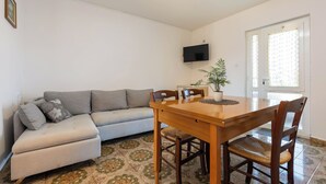 A living room with a sofa, a wooden dining table, and chairs. - Stancija Lindi (Porec)