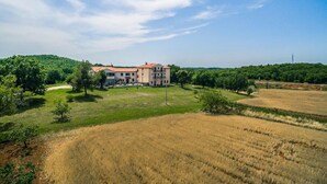 A large building with a red roof, surrounded by green fields and trees. - Stancija Lindi (Porec)