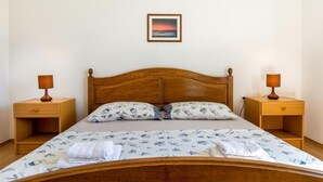 A single bed with a wooden headboard, two bedside tables with lamps, a pillow with a nautical pattern, and a framed picture on the wall. - Stancija Lindi (Porec)