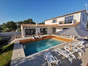 Ein modernes Haus mit Schwimmbad, Außenbereich und einer Terrassenfläche.