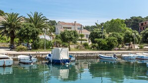 A marina with several boats docked, a white building with a red roof, and lush greenery in the background. - House Kaliope (Zadar)