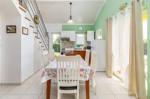 Un comedor con una mesa dispuesta para dos, una escalera y una cocina al fondo.