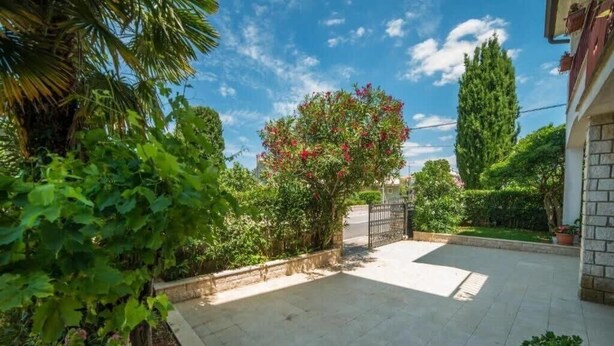 A courtyard with a paved area, a gate, and various plants including a flowering tree. - Guest House Marica (Rovinj)