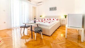 A bedroom with a bed, bedside table, and a small table with chairs. - Guest House Marica (Rovinj)