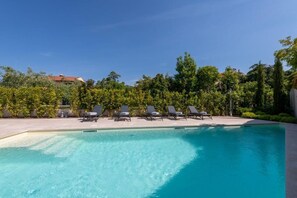 Ein klares Schwimmbecken mit Liegestühlen und einem angelegten Garten.