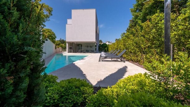 A modern building with a swimming pool, surrounded by lush greenery and a clear blue sky. - Villa Rm (Rovinj)