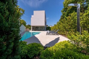 A modern building with a swimming pool, surrounded by lush greenery and a clear blue sky. - Villa Rm (Rovinj)