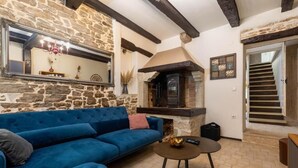 Ein gemütliches Wohnzimmer mit Steinwand, blauem Sofa, Kamin und Treppe.