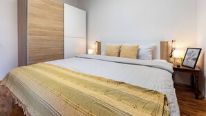 A bedroom with a bed, bedside tables, a nightstand, and a wardrobe.