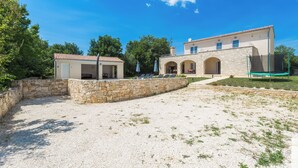 A two-story building with a stone facade, a covered patio area with seating, and a gravel courtyard. - Villa Diletta (Kanfanar)