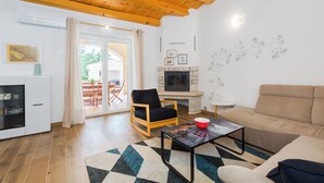 A living room with a wooden ceiling, a sofa, a coffee table, a TV, and a fireplace. - Villa Diletta (Kanfanar)