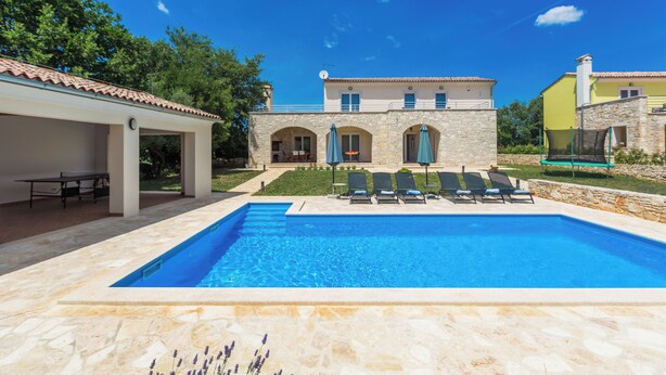A swimming pool with lounge chairs, a covered patio, and a stone building with a tiled roof. - Villa Diletta (Kanfanar)
