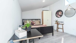 Une chambre à coucher moderne avec un lit, une table de chevet et un petit espace bureau.