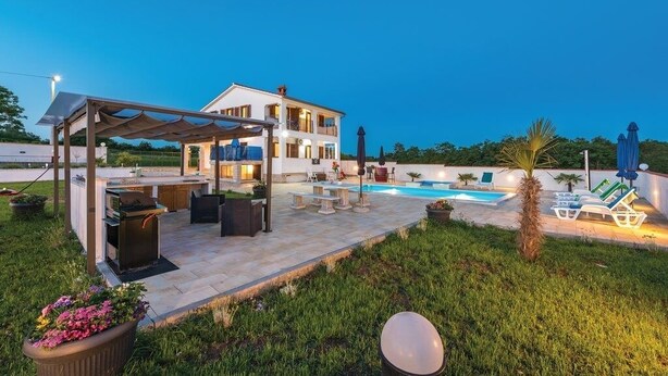 Una casa de dos plantas con un patio trasero, piscina y mobiliario de exterior.
