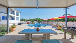Un área de piscina al aire libre con una mesa y sillas, sillones de descanso y una mesa de fútbol.