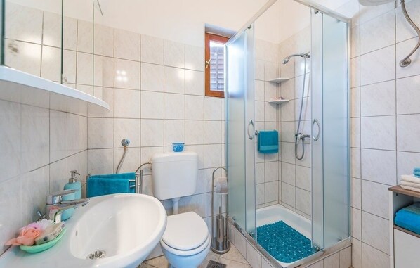 Une salle de bain moderne avec une douche à parois de verre, un lavabo blanc et des toilettes.