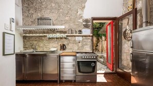 Una cocina compacta con electrodomésticos de acero inoxidable, piso de ladrillo y pared de piedra.