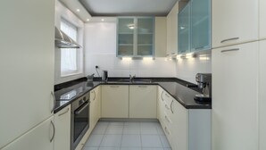 A modern kitchen with white cabinets, black countertops, and stainless steel appliances. - Apartment Elegant (Rovinj)