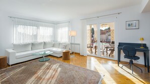A modern living room with a white sofa, glass coffee table, and a patterned rug. - Apartment Elegant (Rovinj)