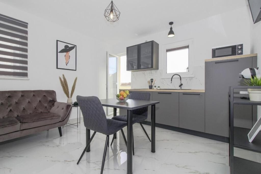 A modern kitchen with a dining area, featuring a sofa, dining table, and chairs.