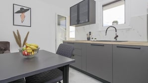 A modern kitchen with grey cabinets, a black countertop, a window, and a framed artwork on the wall. - Apartments Doris (Rovinj)