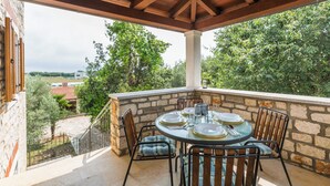 A covered outdoor dining area with stone walls, a wooden ceiling, and a view of the countryside.