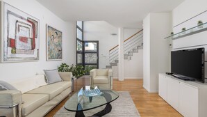 A modern living room with a glass coffee table, a sofa, a TV, and artwork on the walls. - RM Grande Villa (Rovinj)