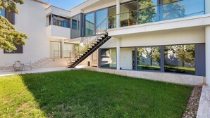 A modern two-story house with a staircase leading to the upper floor, large windows, and a well-maintained lawn. - RM Grande Villa (Rovinj)