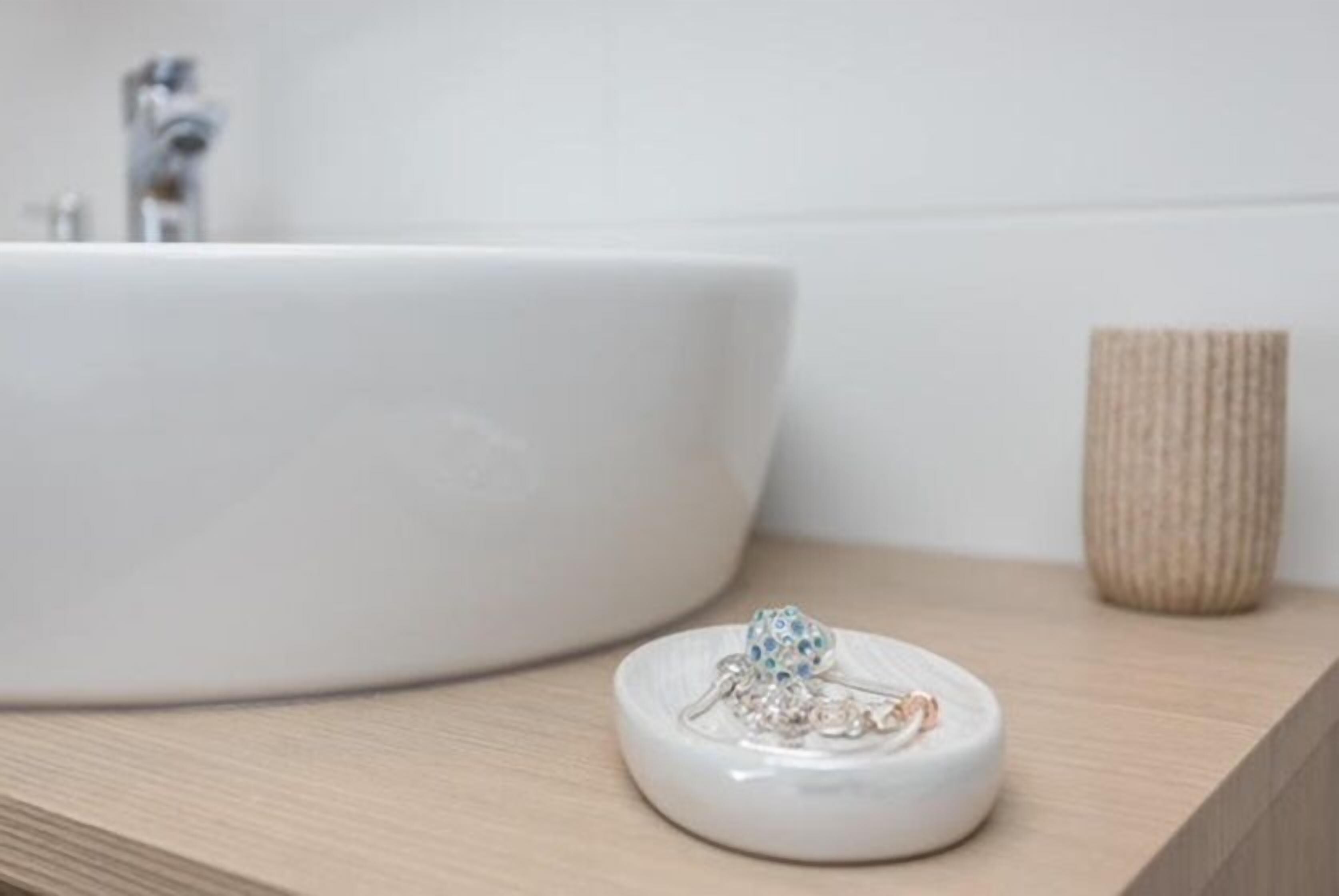 A white sink with a decorative item on a wooden surface.