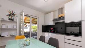 Una cocina moderna con armarios blancos, un horno negro y una mesa de comedor de vidrio.