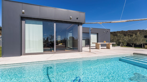 A modern building with large glass doors and a swimming pool in front. - Villa Lagoderan (Rovinj)