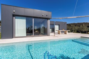 A modern building with large glass doors and a swimming pool in front. - Villa Lagoderan (Rovinj)