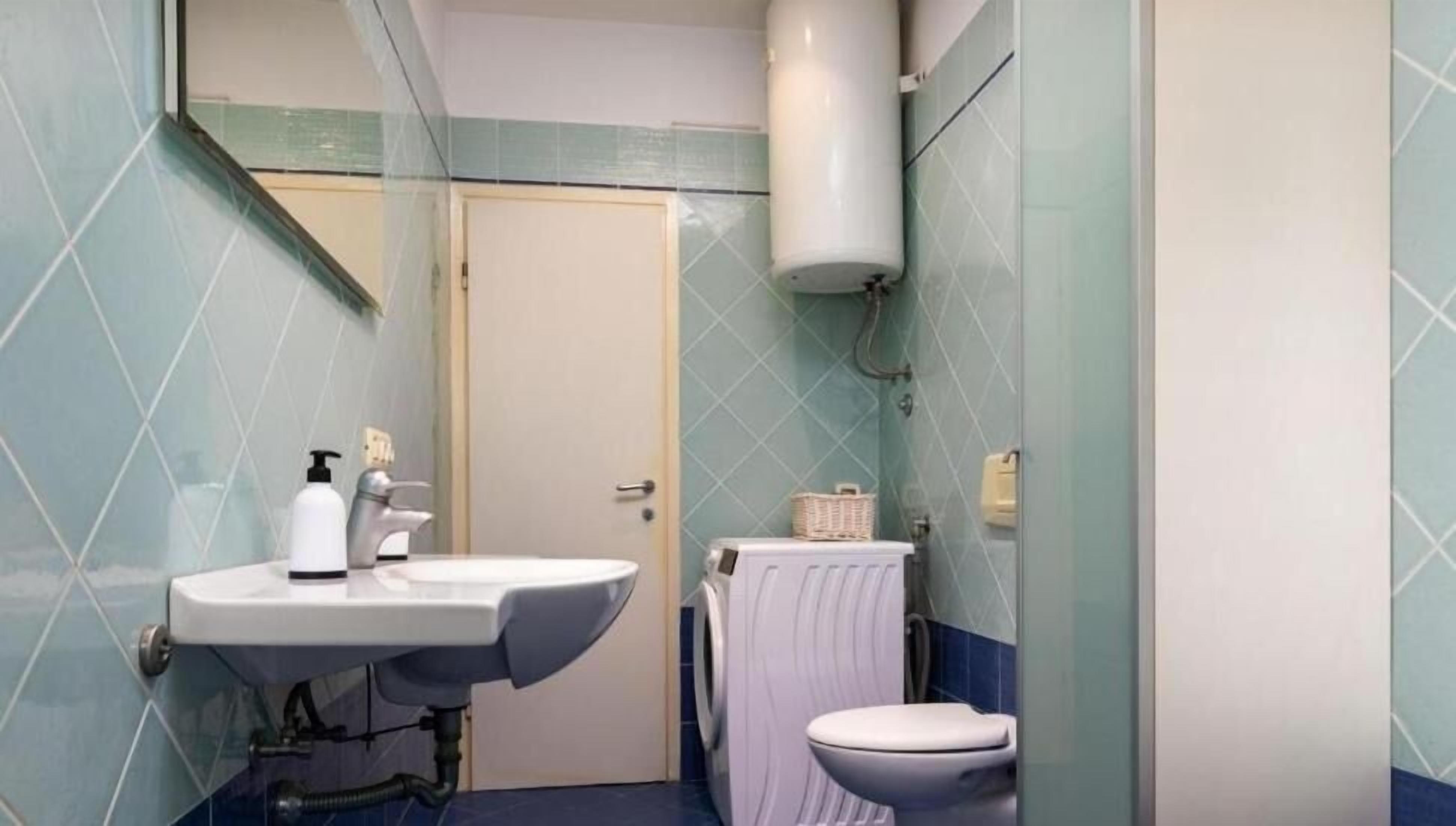A compact bathroom with a sink, toilet, and a washing machine.