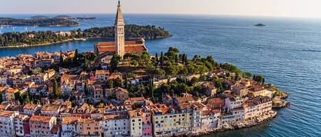 A coastal town with a prominent church tower, surrounded by colorful buildings and a clear view of the sea.