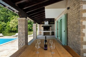 Un patio al aire libre con chimenea de piedra, piscina y sillas de descanso.