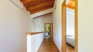 Ein schmaler Korridor mit Holzdielen, der zu einem Schlafzimmer mit einem Bett führt.