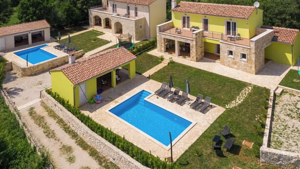 Una villa con piscina, mobiliario de exterior y jardín.