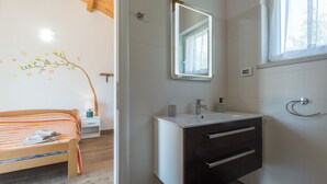 Un dormitorio con cama, mesita de noche, espejo en la pared y ventana.