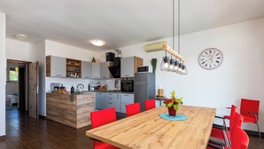 Una cocina moderna con una isla central, sillas rojas y una mesa de comedor de madera.