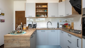 Una cocina moderna con armarios blancos, encimera de madera y repisa incorporada sobre el lavabo.