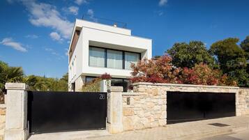 A modern two-story house with a stone wall and a black gate.
