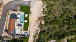 An aerial view of a modern house with a swimming pool, a covered patio, and a well-maintained lawn. - Villa Atrium (Labin)