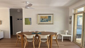 A dining area with a round table, wooden chairs, a ceiling fan, and artwork on the walls. - Annette's - by Lifestyle. Brunswick Heads (BRUNSWICK HEADS)